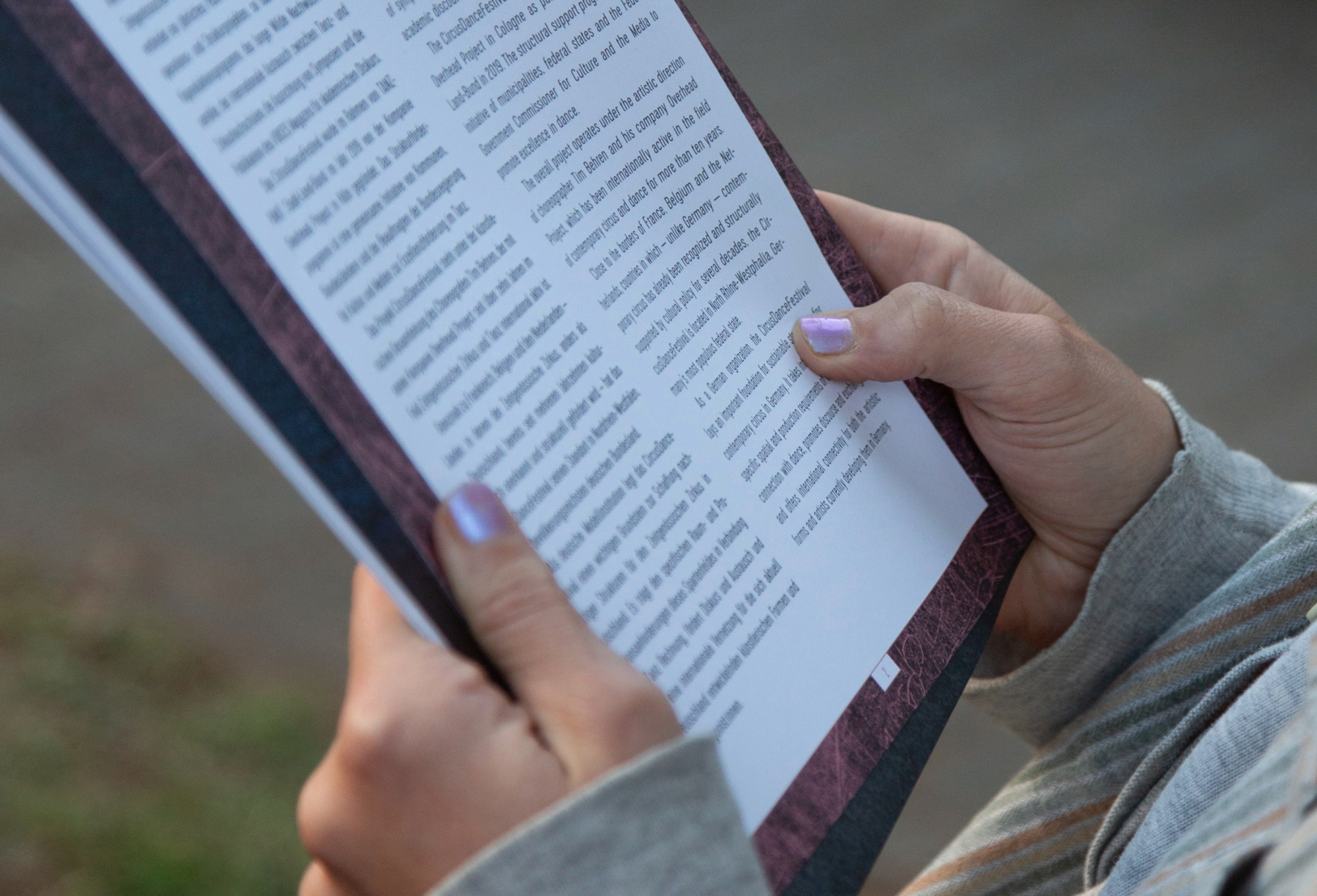 Eine Person hält ein Buch und liest eine Seite mit Fließtext.