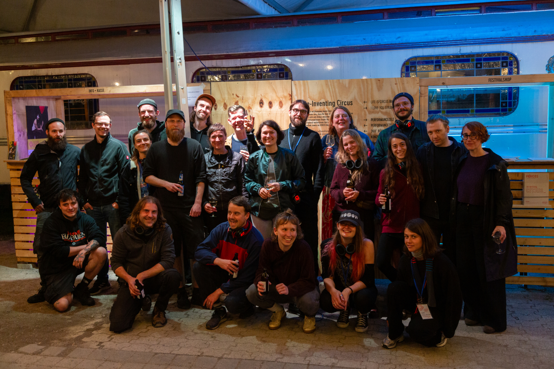 Eine Gruppe von Menschen posiert lächelnd für ein Foto vor einem Veranstaltungsstand.
